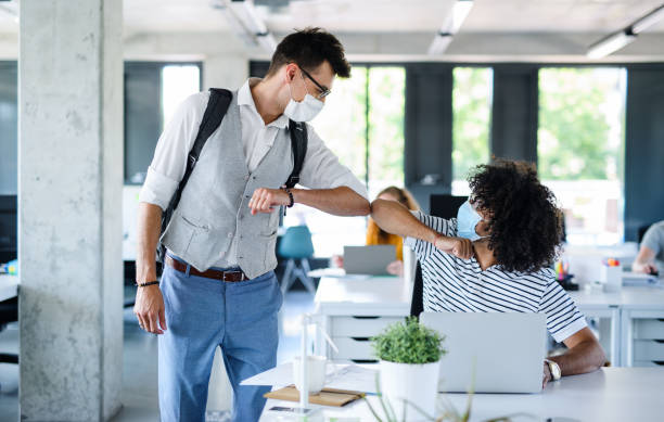 istock Young people with face masks back at work in office after lockdown, greeting. 1249879223