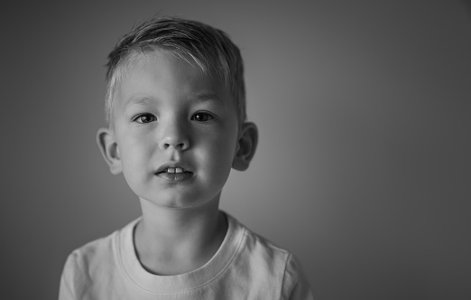 A portrait of a seven month old, Hispanic baby boy wearing a diaper, top hat and bow tie. He is sitting and looking at the camera. Shot in the studio and isolated on a white background.