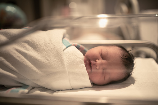 Newborn baby girl sleeping in hospital bed.