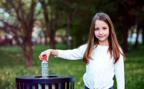 istock Little girl throwing bottle into the trash. Ecology concept 1249882364