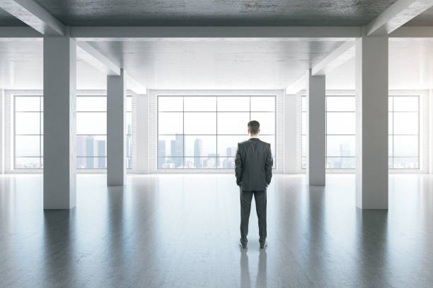istock Businessman standing in modern interior with concrete columns 1249883516