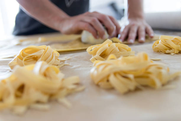 istock Woman kneading pasta dough with pasta in front 1249883917
