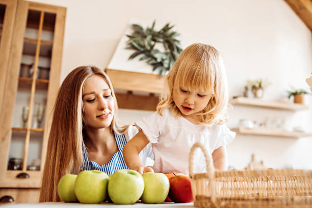 istock Little girl helps mom choose apples at the kitchen table 1249884813