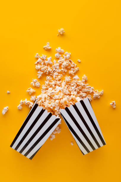 istock Popcorn in paper bag scattered on yellow background top view 1249885522