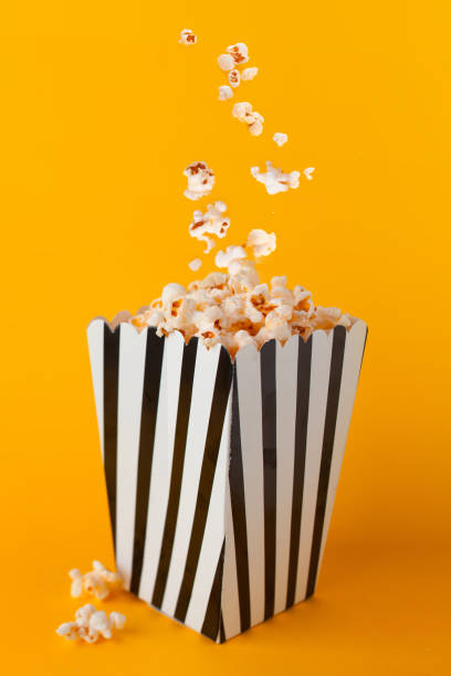 istock Popcorn in paper bag stand on yellow background. 1249885559