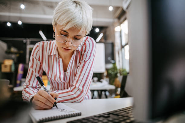 istock Short haired woman designing in notepad in office 1249890658