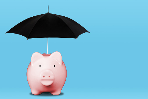 Saving for a rainy day with pink piggy bank and umbrella. Concept of financial security, savings, insurance coverage, wealth management, etc.