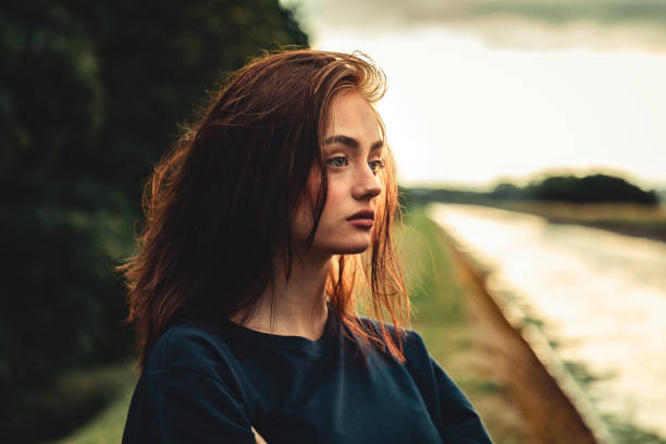 Day Dreaming Sad Looking Teenage Woman Outdoors in Sunset Twilight stock photo