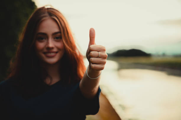 istock Smiling Woman Thumbs Up Handsign Outdoors in Sunset Light 1249899666