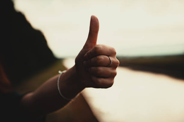 istock Woman Thumbs Up Handsign Outdoors in Moody Sunset Light 1249900922