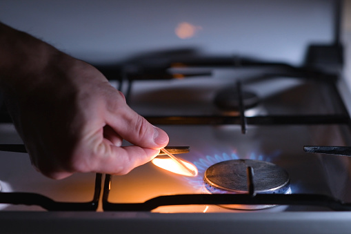 A man lights a gas stove with a match, close-up. Gas ignition
