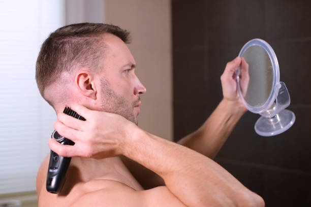 istock a young man cuts himself, using reflection mirrors and a hair clipper 1249904819