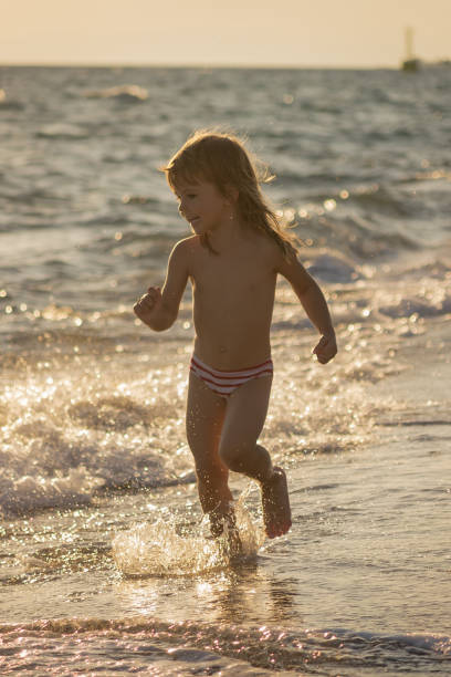little girl running in the shallow water at the seaside