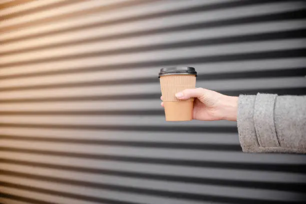 Woman female hand with coffee cup paper latte. Cup in a holder, coffee cup to go takeaway.