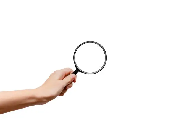 Photo of Femal hand holding magnidying glass. Detective and searchConcept. White background, isolated, close up