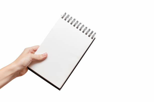istock Femal hand holding white sketchbook . Educational and creativeConcept. White background, isolated, close up 1249910724
