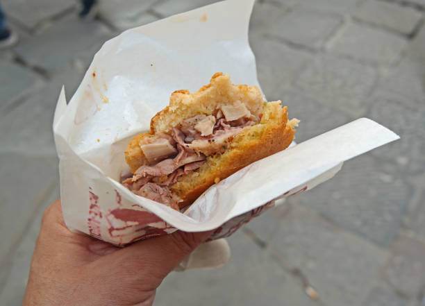 A tripe sandwich being held in a left hand on the street in Florence, Italy
