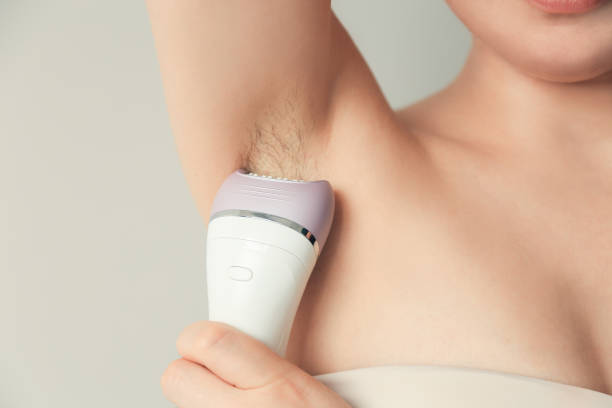 Woman depilated armpits with an epilator Woman takes care of herself, depilated armpits with an epilator. Epilation Cosmetology procedure for hair removal. SPA concept. epilator stock pictures, royalty-free photos & images