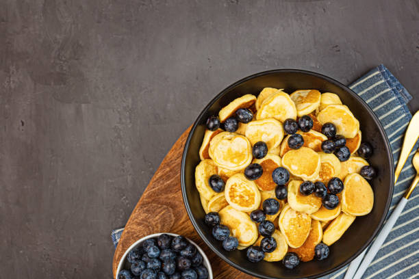 istock Trendy home breakfast with tiny pancakes and blueberry on gray concrete background. Flat lay, top view, overhead, mockup, template, copy space. View from above 1249925746