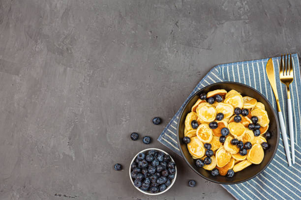istock Trendy home breakfast with tiny pancakes and blueberry on gray concrete background. Flat lay, top view, overhead, mockup, template, copy space. View from above 1249925766