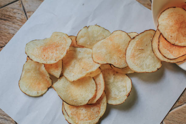 istock Fresh Crispy potato chips on a wooden background, top view. Salty crisps scattered on a table for a tasty snack break. 1249925806