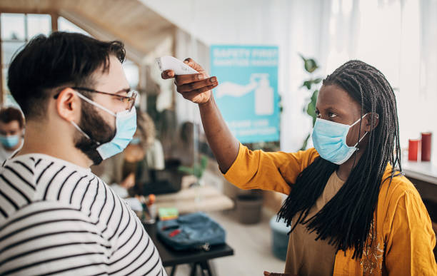 istock Colleagues with protective masks measuring body temperature in office 1249929039