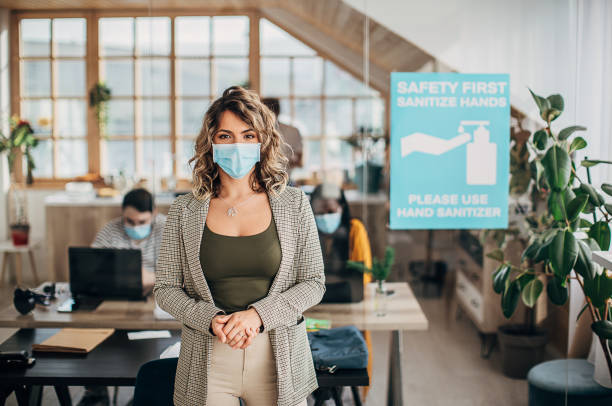istock Beautiful woman with protective mask standing in office 1249931482
