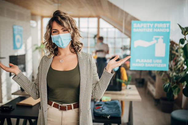 istock Beautiful woman with protective mask standing in office 1249931554