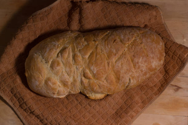pão caseiro em uma toalha de pano marrom na tábua de corte de madeira. - brown bread bread cutting board full length - fotografias e filmes do acervo