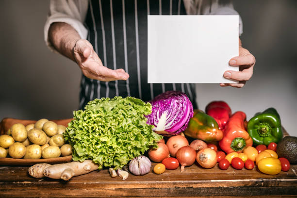 istock Grocer presenting vegetables at grocery with blank sign 1249934453