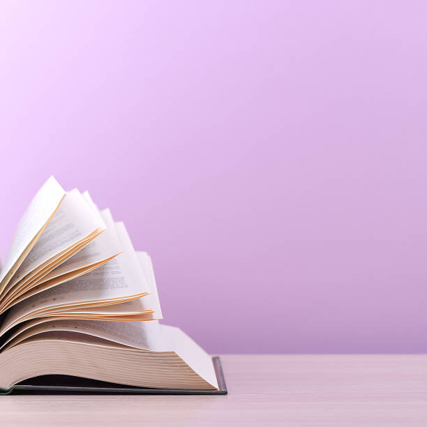 istock The book is open, lying on the table, sheets fanned out on a pink background. 1249936126