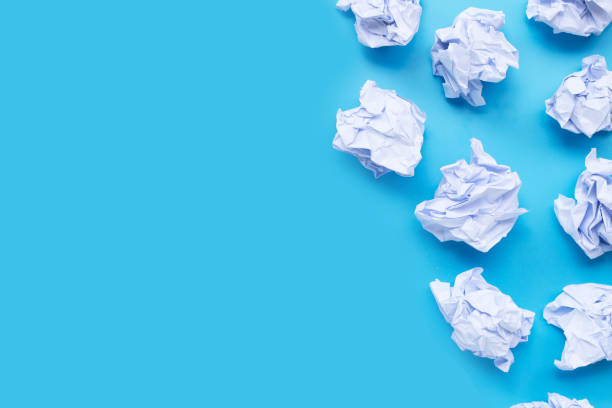 istock White crumpled paper balls on a blue background. 1249937565