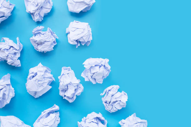 istock White crumpled paper balls on a blue background. 1249939248
