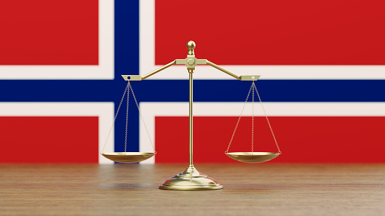 Bronze scale standing in front of Norwegian flag. Horizontal composition with copy space. Front view. Social justice concept.