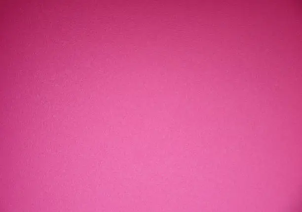 A bright pink monochrome rough surface with vignetting along the edges and a gradient from below. Background, texture.