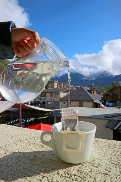 Closeup Hand Pouring Hot Water into the Portable Drip Coffee Bag with Caucasus Mountains View in Background