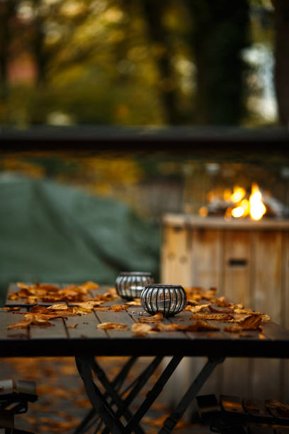 Beautiful garden with fireplace. Table with candles covered by autumn orange leaves. Concept of romantic evening, date, cozy leaving autum light stock pictures, royalty-free photos & images