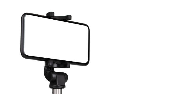istock Smartphone with a white cut-out screen on a monopod. Selfie stick and smartphone on a white background. 1249962430