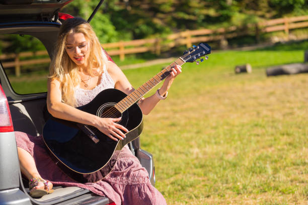 istock Hippie woman playing guitar in van car 1249964745