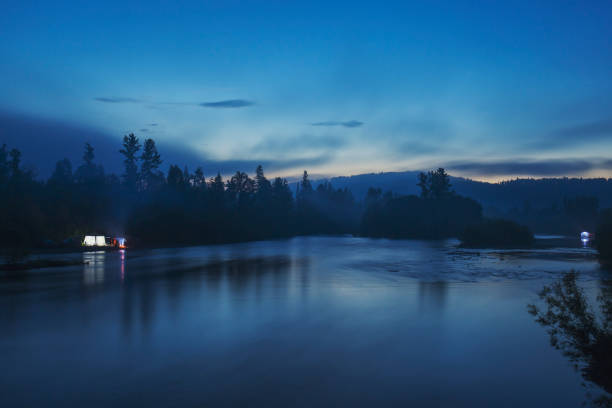 istock Night landscape: wide river, coniferous forest and sky with clouds. 1249964902