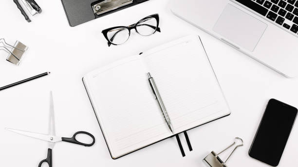 istock Top view white office desk table. Flat lay workspace with eye glasses, laptop, smartphone, clipboard, notebook and a pen, paper clip, pencil, offi supplies on white background 1249967508