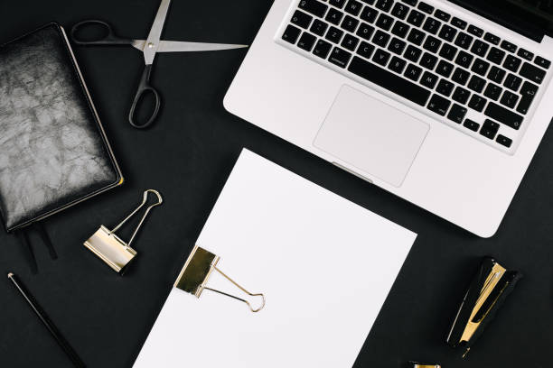 istock Top view of a workspace with laptop computer keyboard, notebook, pen, clipboard and clips on black background. Close up, copy space, background, flat lay 1249967556