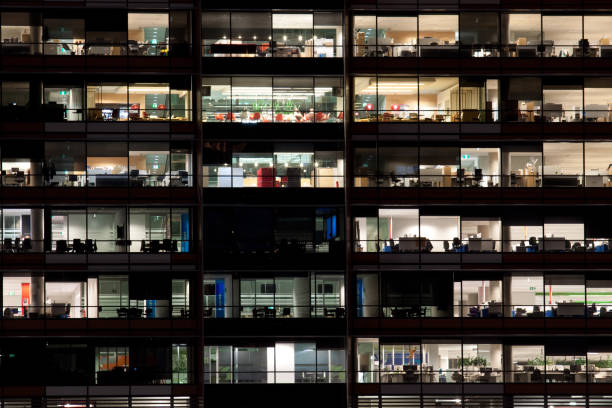 istock Office building windows with lights on at night 1249967595