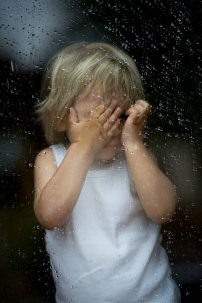 istock Sad child behind the window on rainy day 1249967946