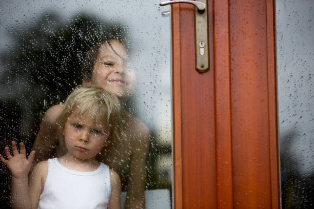 istock Sad child behind the window on rainy day 1249968139