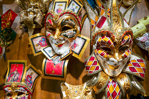 Venice, Italy - March 01, 2022: Couple dressed in traditional costumes stand in front of the Ducal palace, part of the Venice Mask Carnival, Veneto, Italy