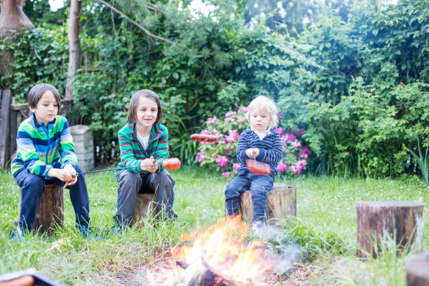 istock Happy kids roasting sausages on campfire 1249969189