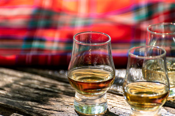 Tasting of different Scotch whiskies on outdoor terrace, dram of whiskey and red tartan Tasting of different Scotch whiskies on outdoor terrace, dram of whiskey and red tartan close up glass of bourbon stock pictures, royalty-free photos & images