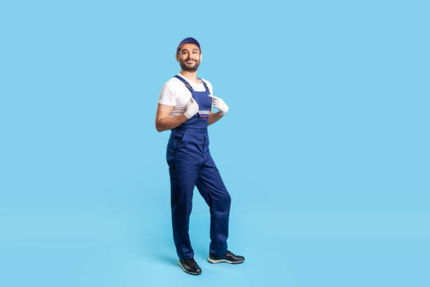 Full length self-confident professional handyman in overalls pointing himself and looking with arrogance