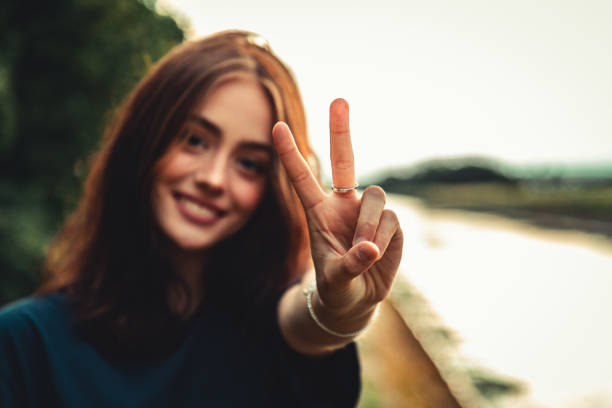 le sourire de femme adolescente de paix handsign à l’extérieur dans la lumière de coucher du soleil - symbols of peace photos et images de collection